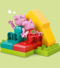 Peppa Pig ja George -LEGO Duplo -hahmot istuvat värikkäiden palikoiden päällä keltaisen kolmion edessä.