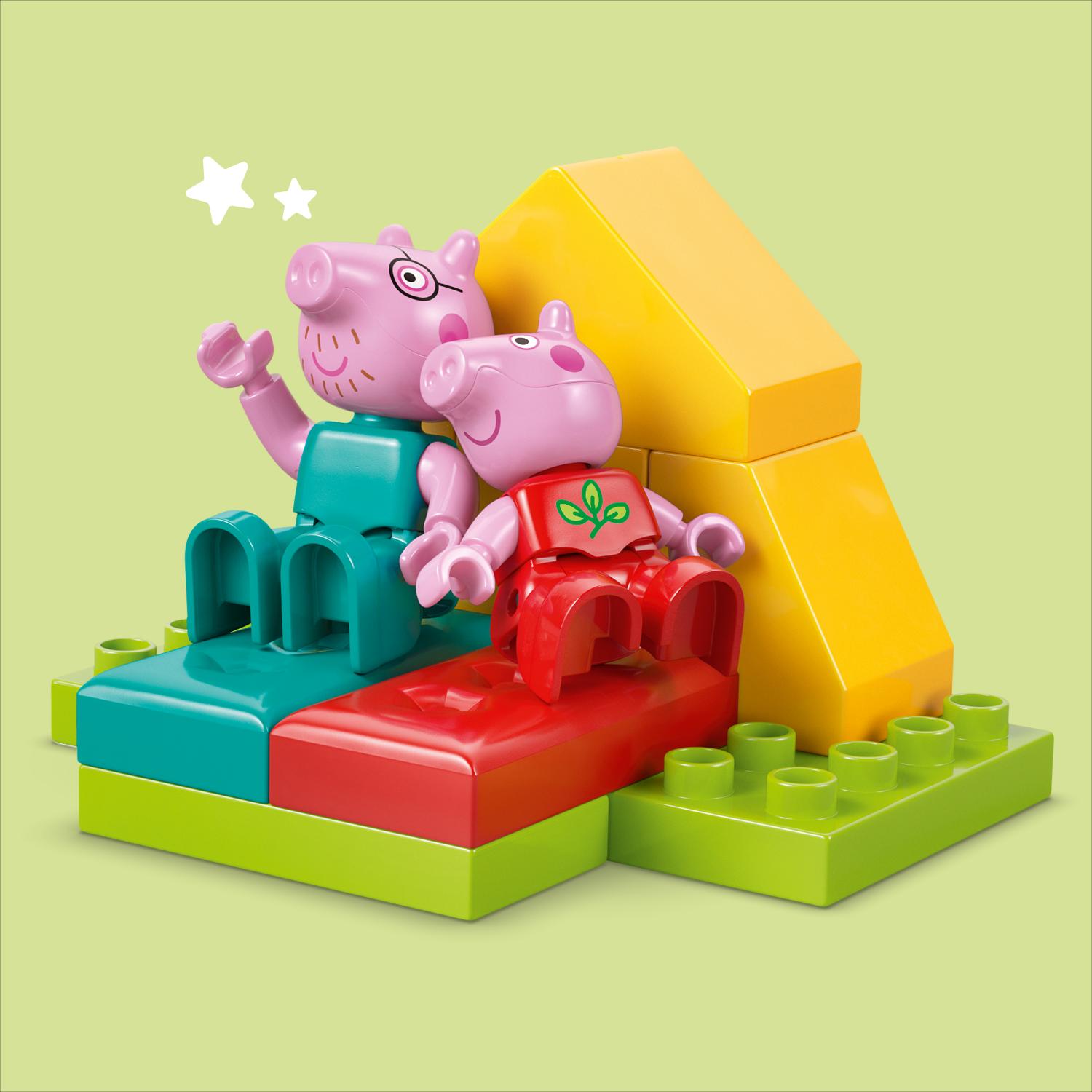 Peppa Pig ja George -LEGO Duplo -hahmot istuvat värikkäiden palikoiden päällä keltaisen kolmion edessä.