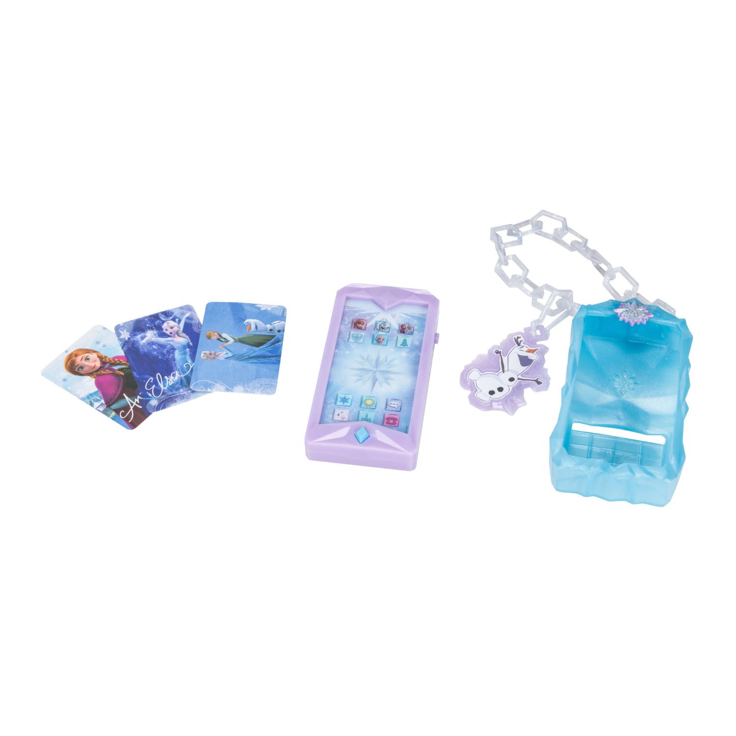 Frozen-aiheinen lelusetti, jossa on kolme hahmokorttia, violetti puhelinta muistuttava kädessä pidettävä laite sekä sininen muovikotelo, jossa on valkoinen ketju ja violetti lumihiutale-riipus, kaikki valkoisella taustalla.