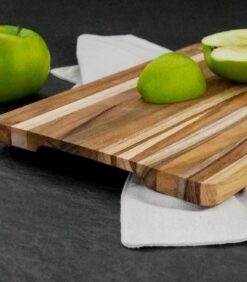 Valkoiselle liinalle on asetettu raidallinen Leikkuulauta lucy tiikkiä 30x20cm -leikkuulauta, jolla on tummalla pohjalla kokonainen vihreä omena, puolikas omena ja omenaviipale.