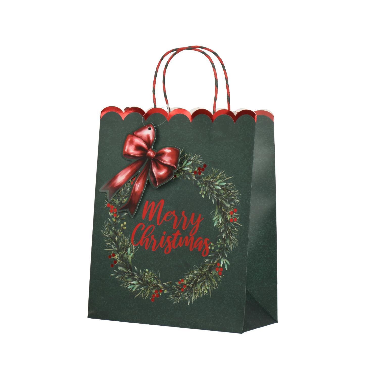Tummanvihreä lahjapussi, jossa on punainen kantokahva; etupuolella on seppele, punainen rusetti ja teksti ”Merry Christmas”.