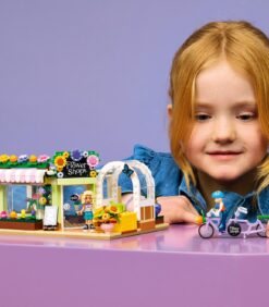 Lapsi rakentaa LEGO Friends -sarjan kukkakauppasetin, johon kuuluu myymälän julkisivu, minihahmo ja polkupyörä.