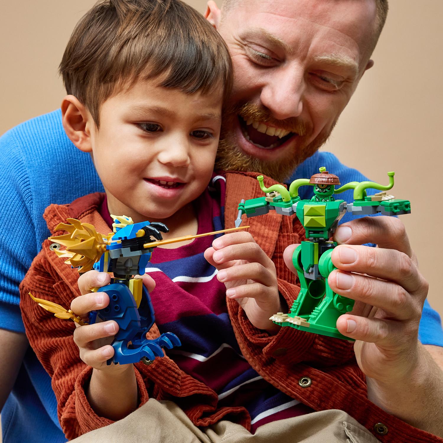 Mies ja pieni poika hymyilevät leikkiessään kahden Lego-olentohahmon kanssa.