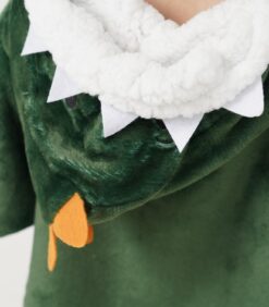Lähikuva vihreästä pehmoleludinosauruspuvusta, jossa on valkoiset huopahampaat, pörröinen valkoinen reunus ja oranssi huopakoriste hupussa.