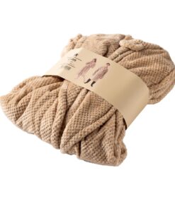 Taitettu, beige, kuvioitu huopa, jossa on hihat, on kääritty kermanväriseen paperinauhaan. Nauhassa on kuvia ihmisistä, jotka käyttävät huopaa kotiasuna.