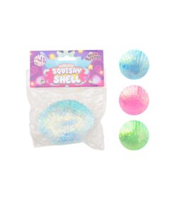 Pakkauksessa oleva Squishy Shell -niminen pehmeä simpukkalelu, jonka vieressä on kolme kimaltelevaa simpukkaa: sininen, vaaleanpunainen ja vihreä.