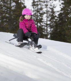 Tyttö laskee lumista mäkeä alas mustalla Stiga Iconic rattikelkalla