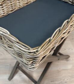 Pajuista punottu kori, jossa on tasainen tumma pinta ja taitettava puinen jalusta.