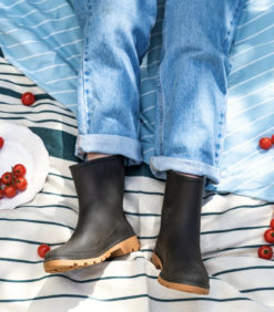 Tummanruskeat kumisaappaat viltillä makaavan ihmisen jalassa.